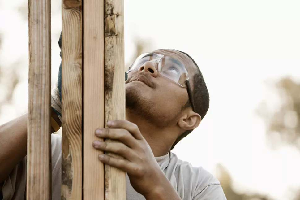 man in safety glasses holding wooden studwork